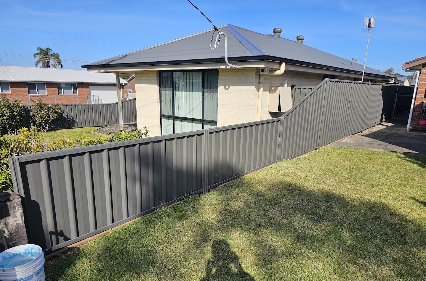 A long Colorbond boundary fence beside a fresh lawn