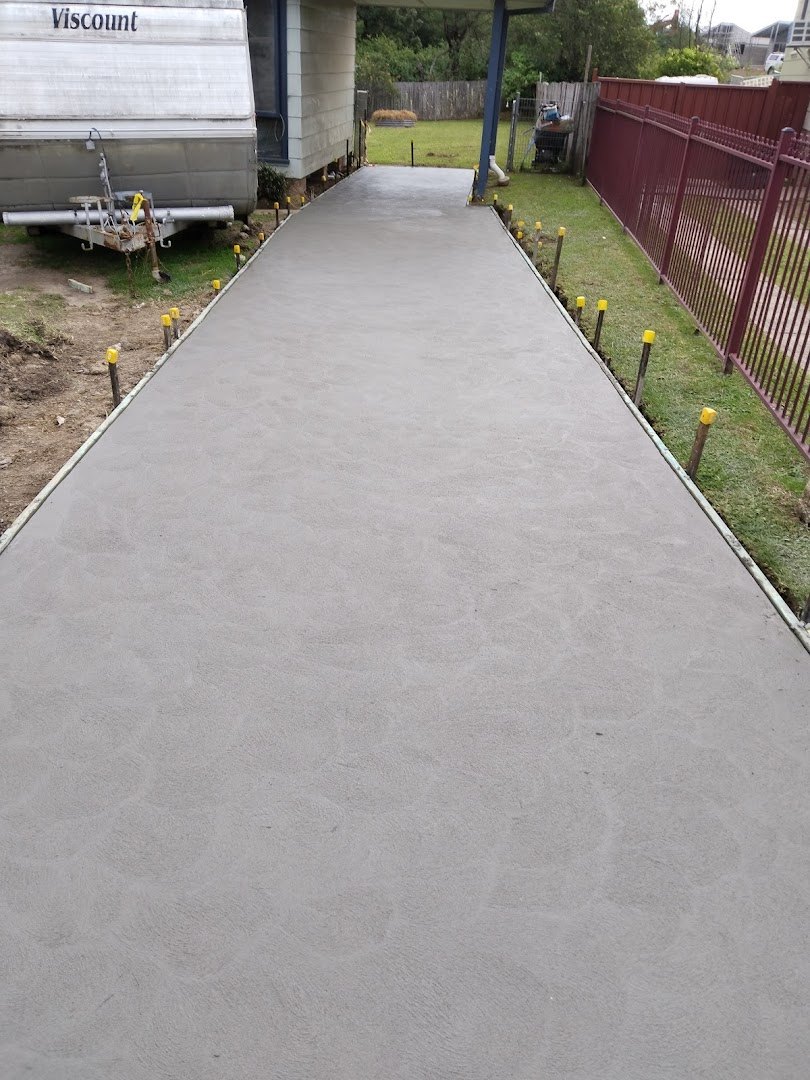 A new concrete path laid beside a red metal fence