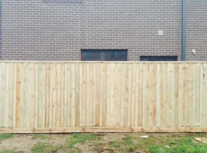 A new timber paling fence in front of a brick building