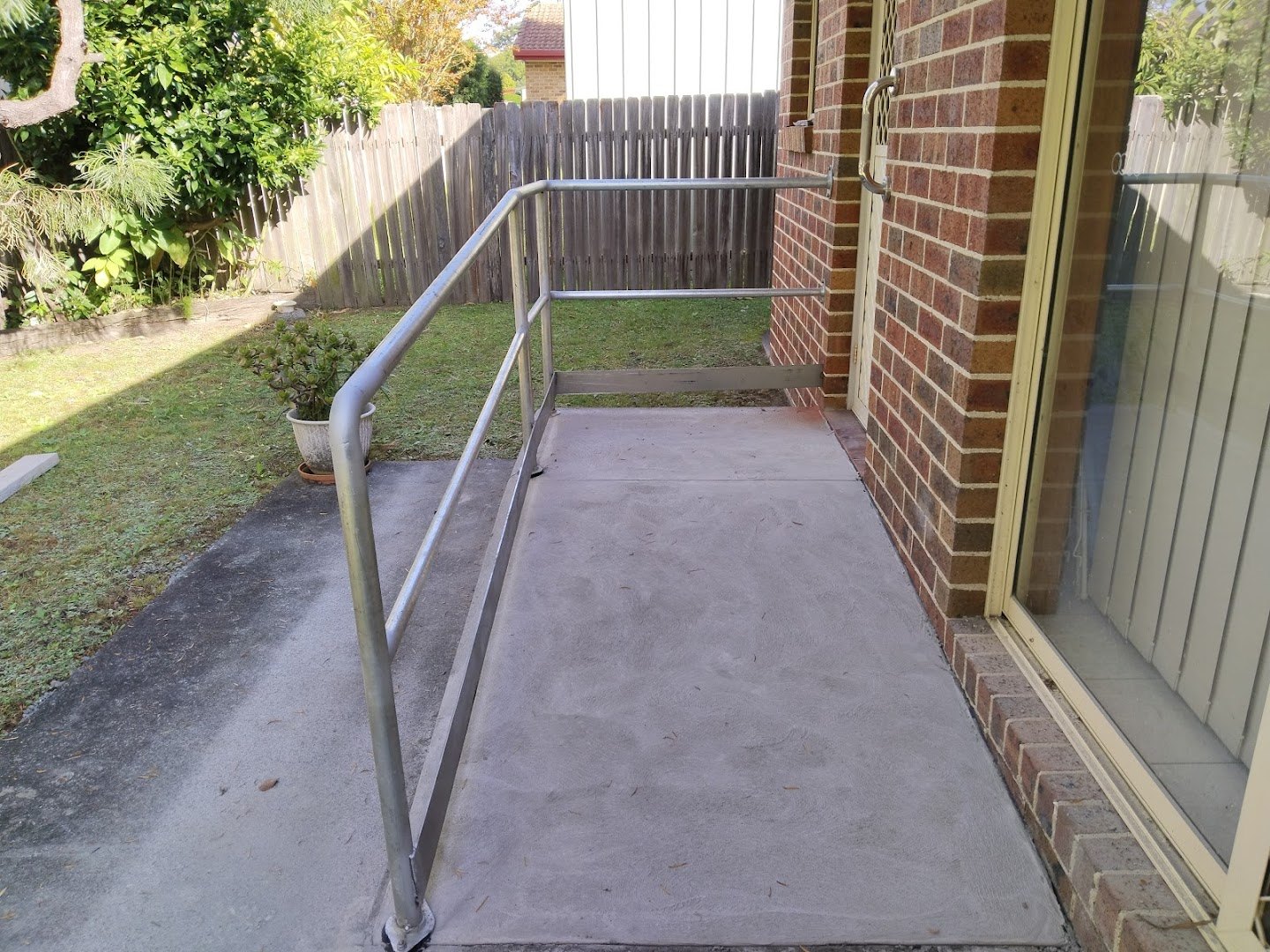 A concrete ramp with a new handrail at a brick home