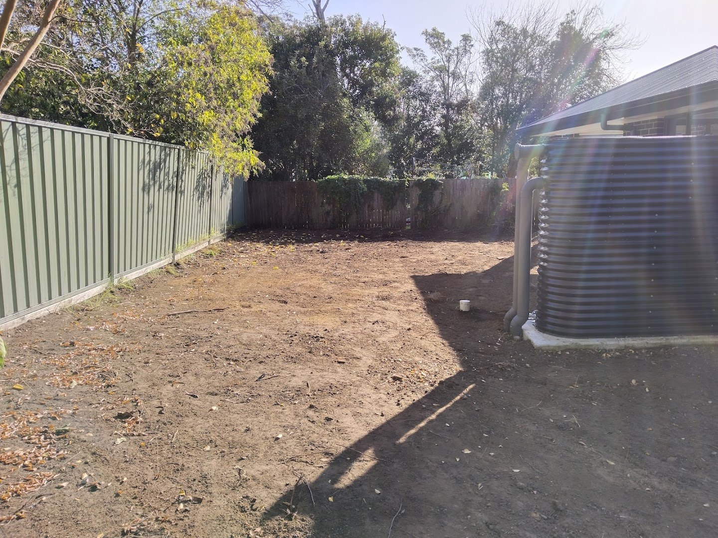 A new Colorbond boundary fence along a cleared backyard