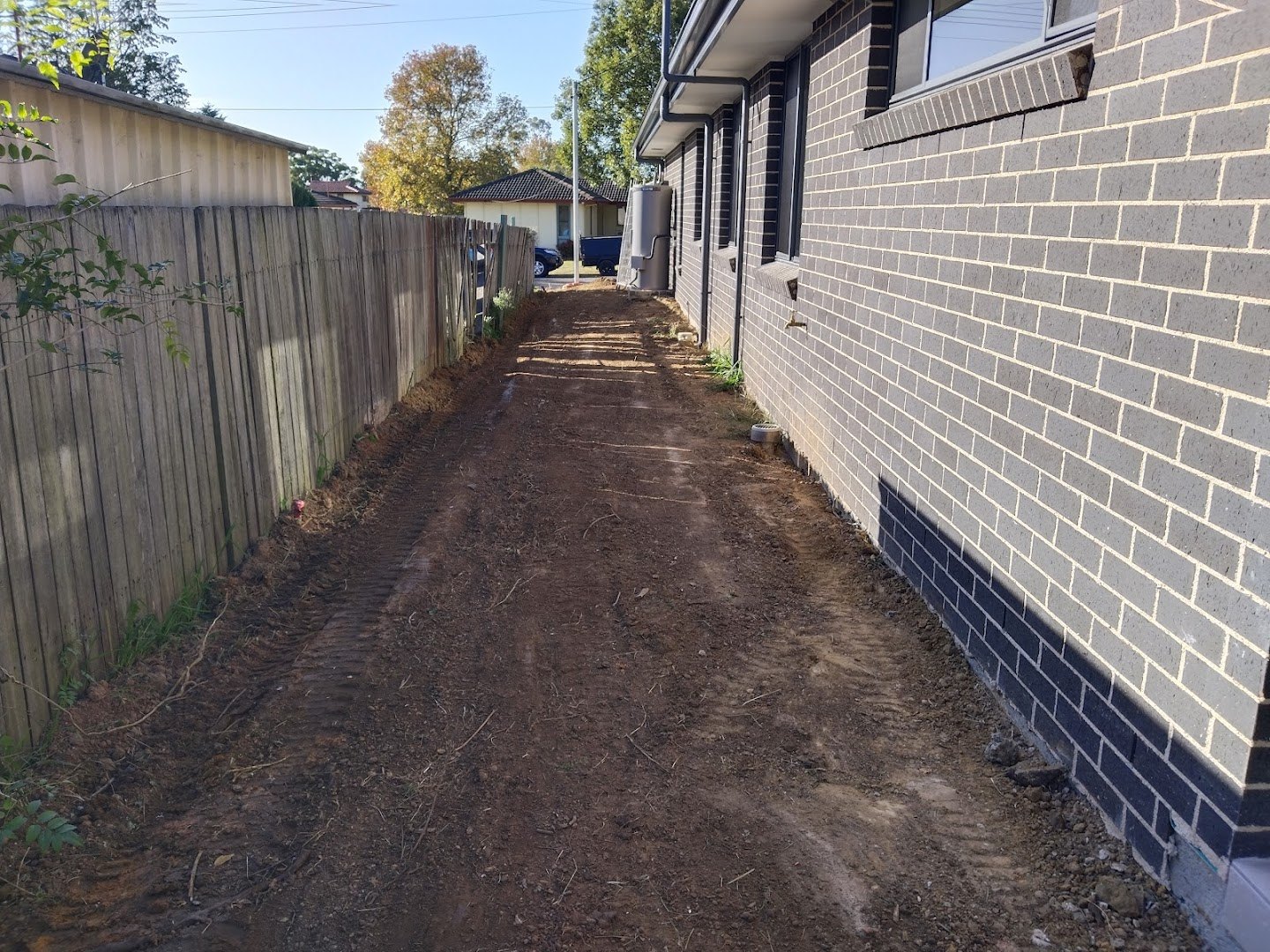 A cleared side yard along a new timber fence